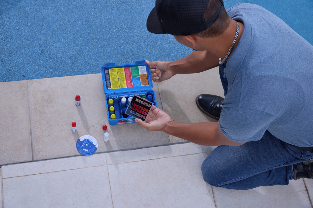 Person next to a swimming pool performing a water quality test with a K-2005 kit